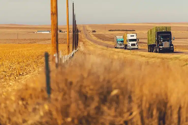 Trucks on highway traveling by farm land